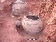 Two intact red-ware burial urns sitting in their original burial pit, photographed during excavation