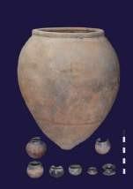 A red-ware burial urn shown alongside the small grave-goods pots that accompanied it