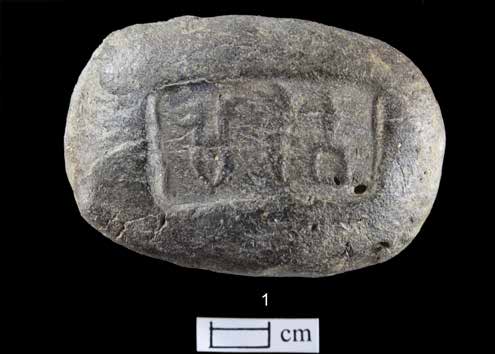 Photograph of a small terracotta sealing impressed with three Harappan script signs