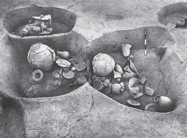 An overhead photograph of two adjacent Harappan pot burials, surrounded by miniature offering vessels